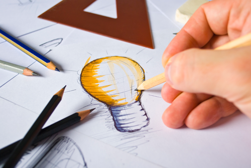 Person drawing a lightbulb logo